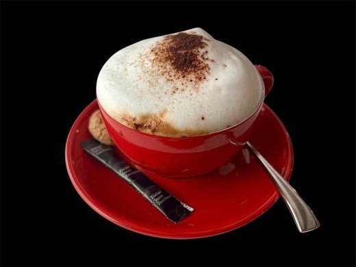 Cappuccino in der roten spuntino-Tasse mit Kakaopulver, Löffel und Cantuccio.