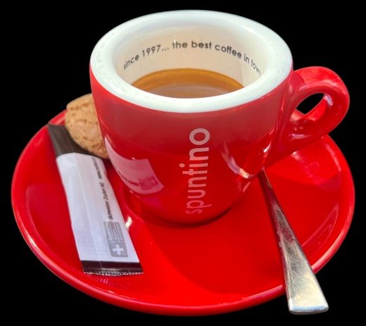 Espresso in der roten spuntino-Tasse auf rotem Untersatz, mit Zucker-Stick und Löffel.